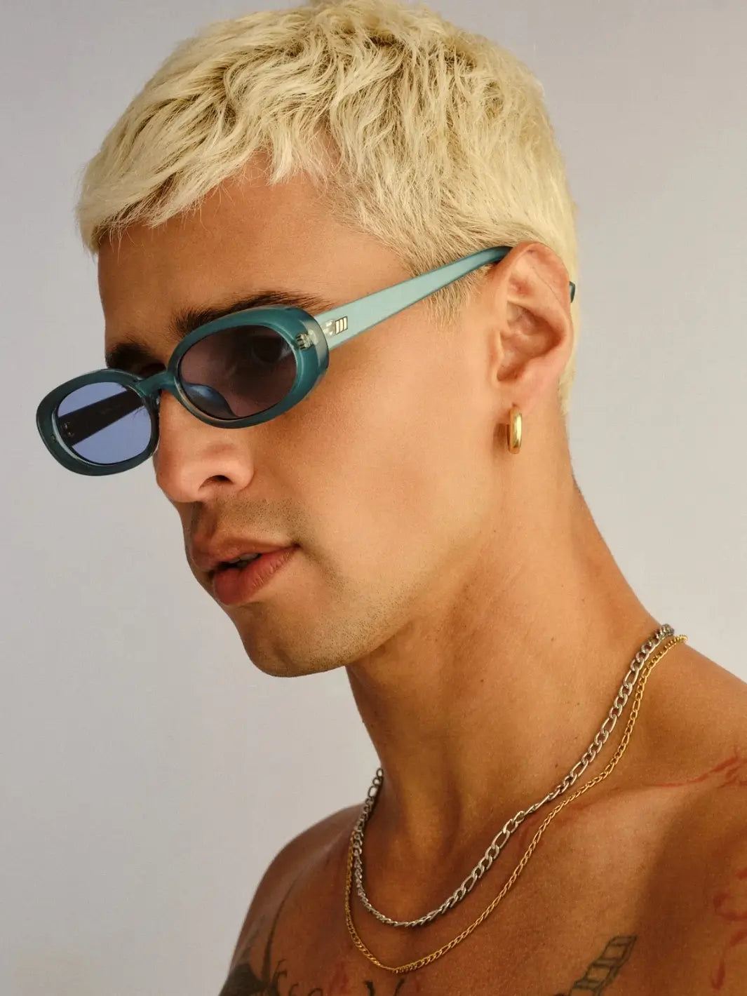 A side profile portrait of a man with blonde hair showcasing the temple arm of the Le Specs Sunglasses Outta Love + in Blue Pearl frames | Twentyseven Toronto