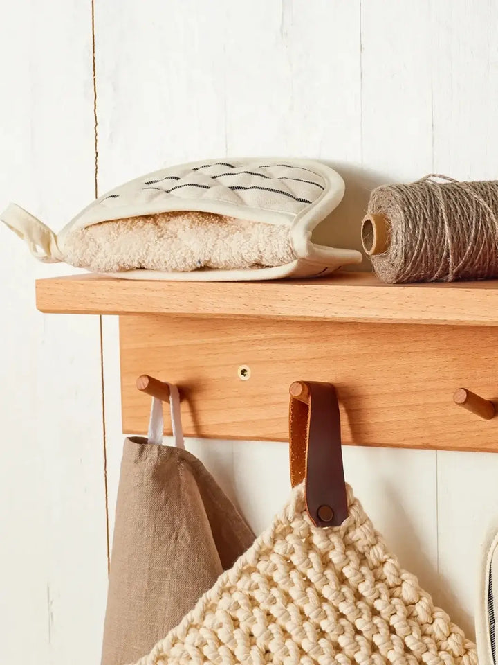 Wooden shelf with hooks holding kitchen items from Burstenhaus Redecker against a white wall | Twentyseven Toronto