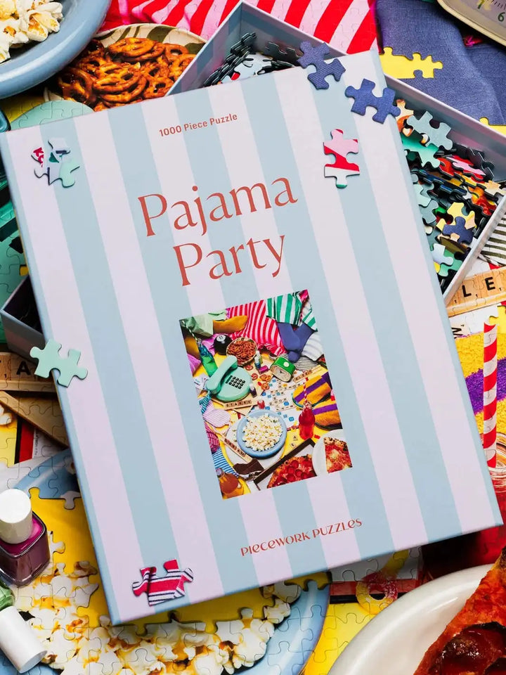 Piecework Puzzles 'Pajama Party' 1000 piece puzzle box with puzzle pieces scattered around | Twentyseven Toronto