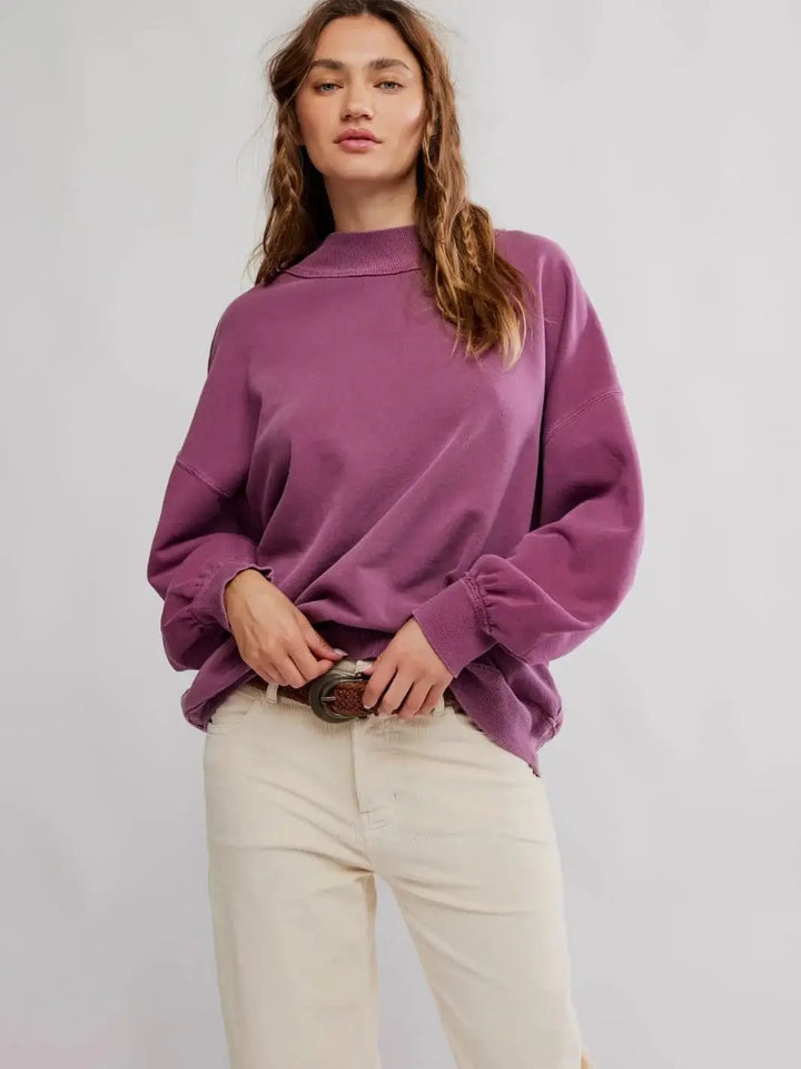 A studio front portrait shows a model wearing the relaxed-fit Jungmaven Palm Springs Pullover in Damson styled with off-white trousers and a brown leather belt | Twentyseven Toronto