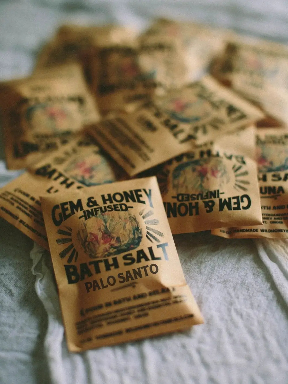 A scattered pile of brown paper packets of the Palo Santo Bath Soak and Body Scrub from Wild Yonder Studio | Twentyseven Toronto