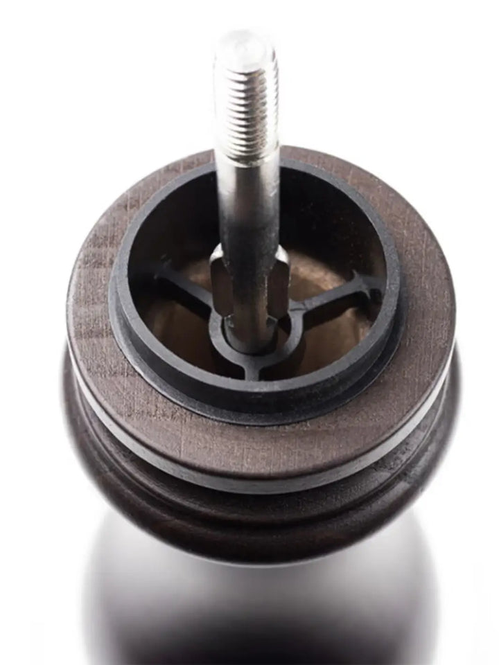 Close-up of a metal wheel from Peugeot 'Paris U'Select Wood Pepper Mill' with a central shaft on a white background | Twentyseven Toronto