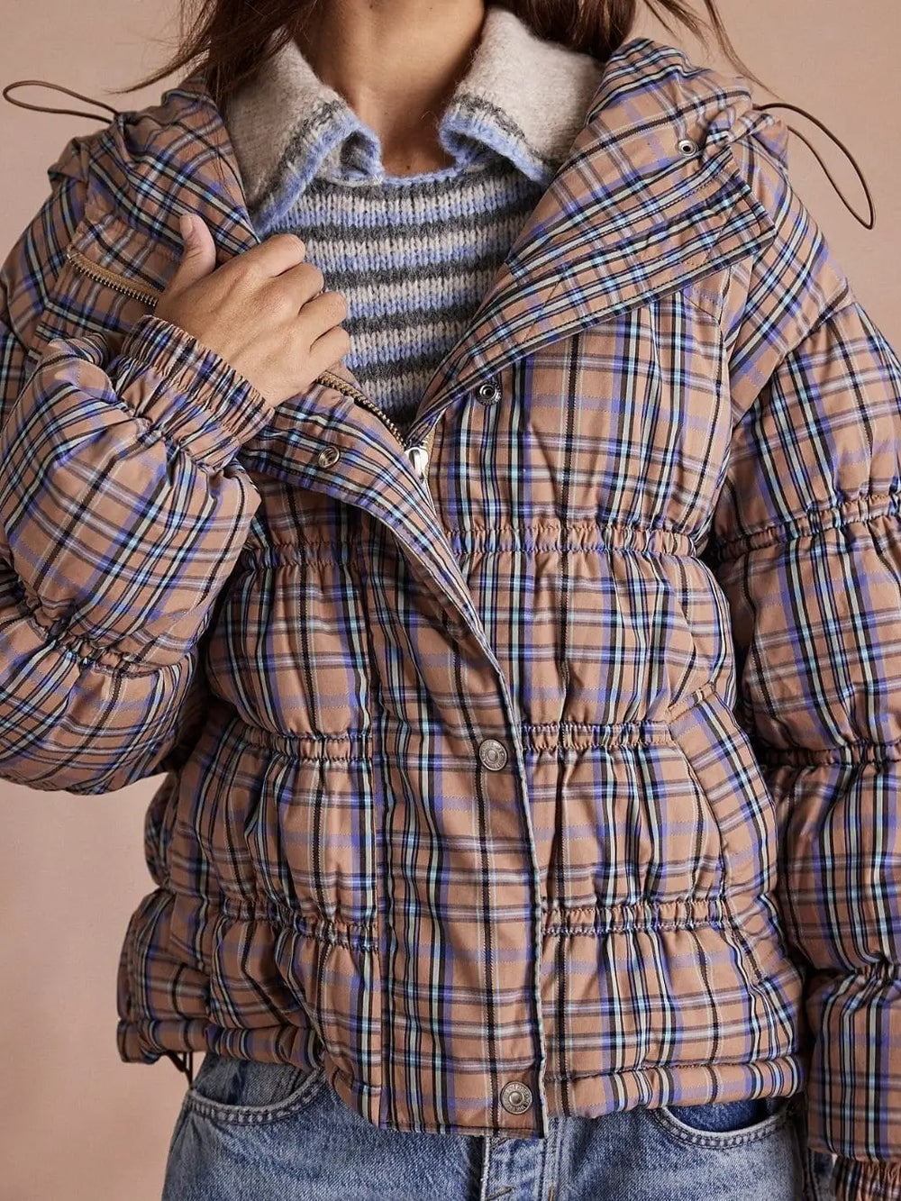 A close-up front shot highlights the buttoned storm placket, elastic cuffs, and cinched waist detailing of the plaid Free People Party Of One Puffer Jacket - Tan Combo | Twentyseven Toronto