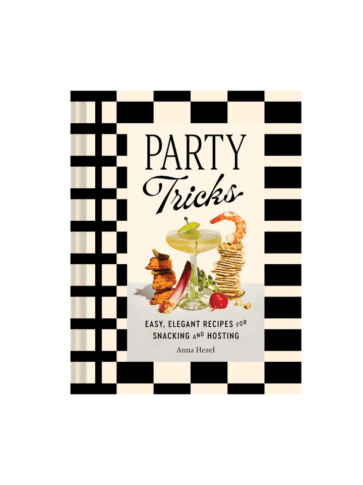 Front cover of Party Tricks: Easy, Elegant Recipes for Snacking and Hosting by Anna Hezel, featuring a black-and-white checkered border and a central photograph of a cocktail glass surrounded by stacked snacks | Twentyseven Toronto