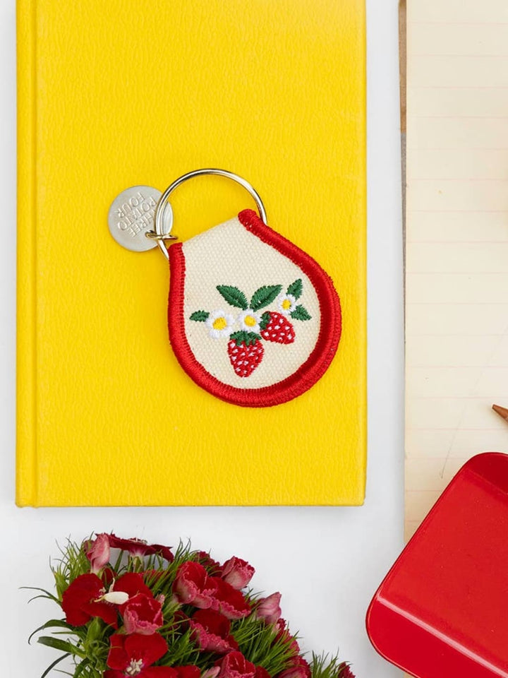 Patch keychain with embroidered strawberry and flower design from Three Potato Four on yellow background | Twentyseven Toronto