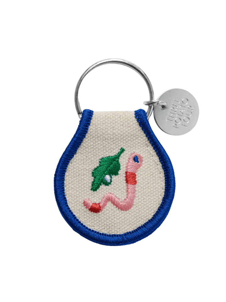 A Three Potato Four Patch Keychain - Worm featuring a pink embroidered worm next to a green leaf | Twentyseven Toronto