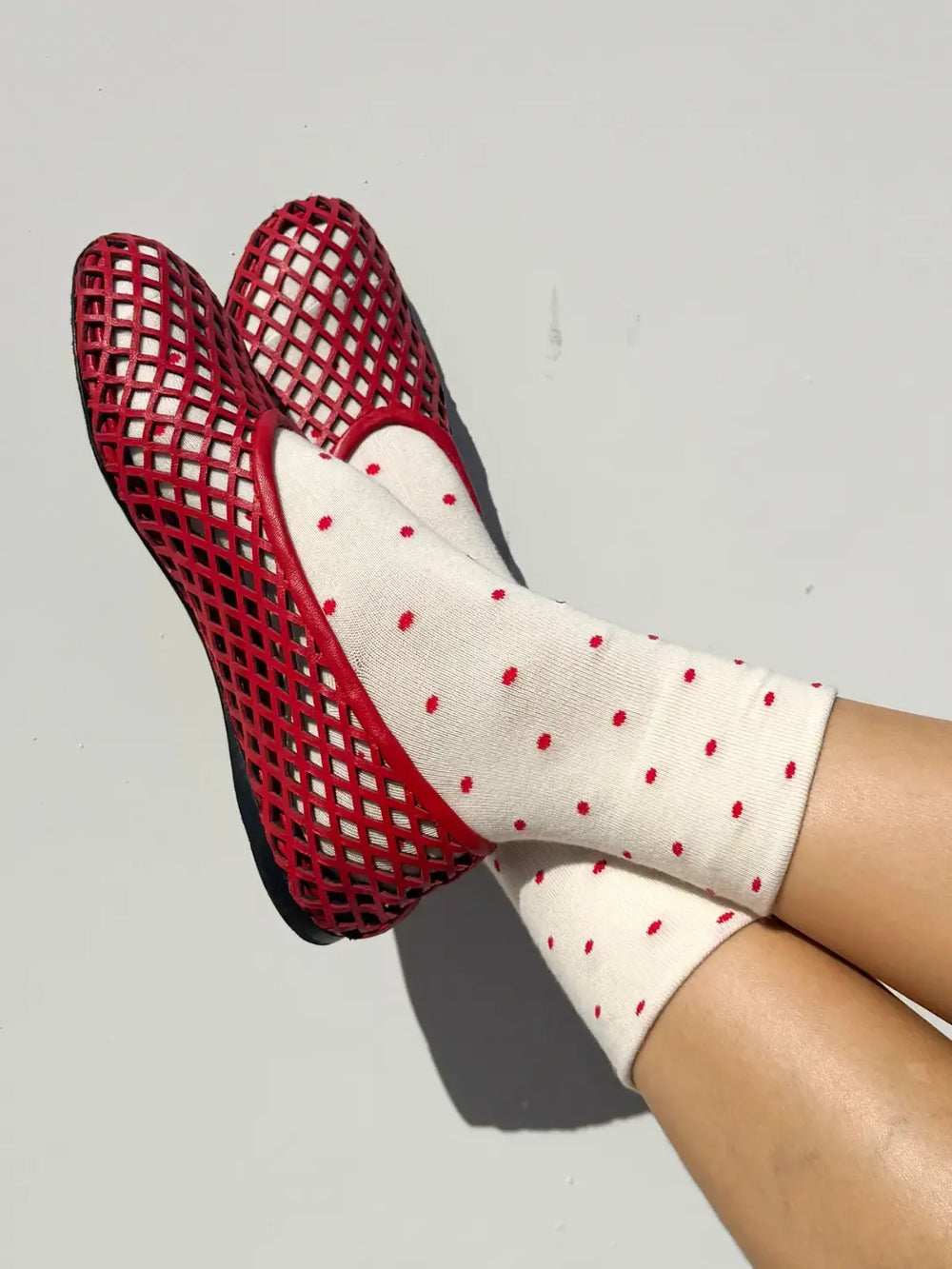 Red mesh shoes and white Le Bon Shoppe Patterned Sneaker Socks with cream and red polka dots on a light gray background | Twentyseven Toronto