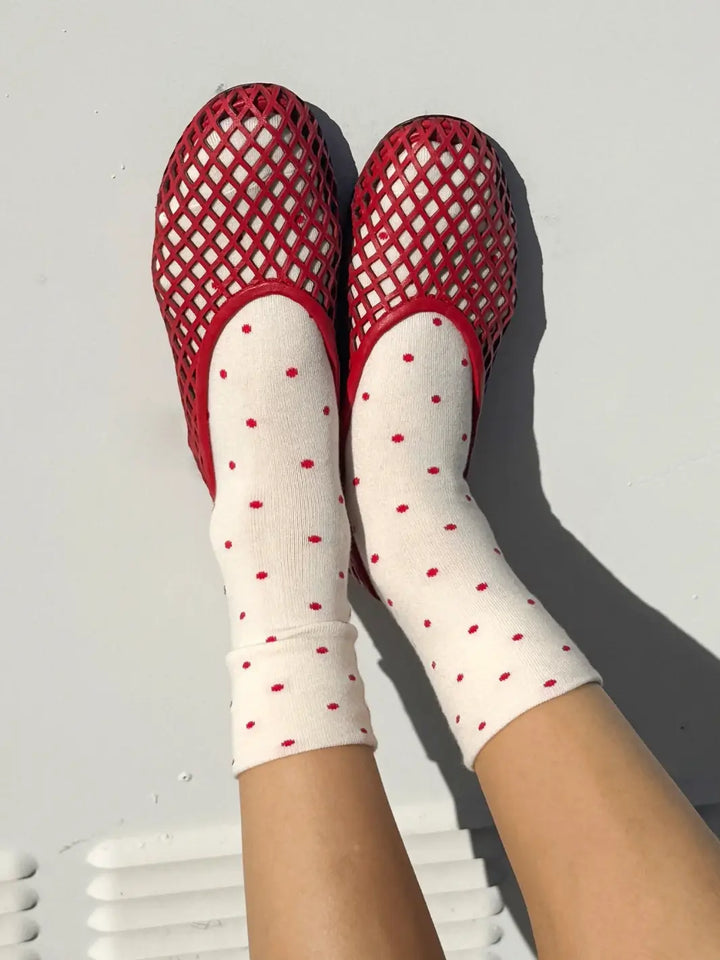Red mesh shoes and white Le Bon Shoppe Patterned Sneaker Socks with cream and red polka dots on a light gray background | Twentyseven Toronto