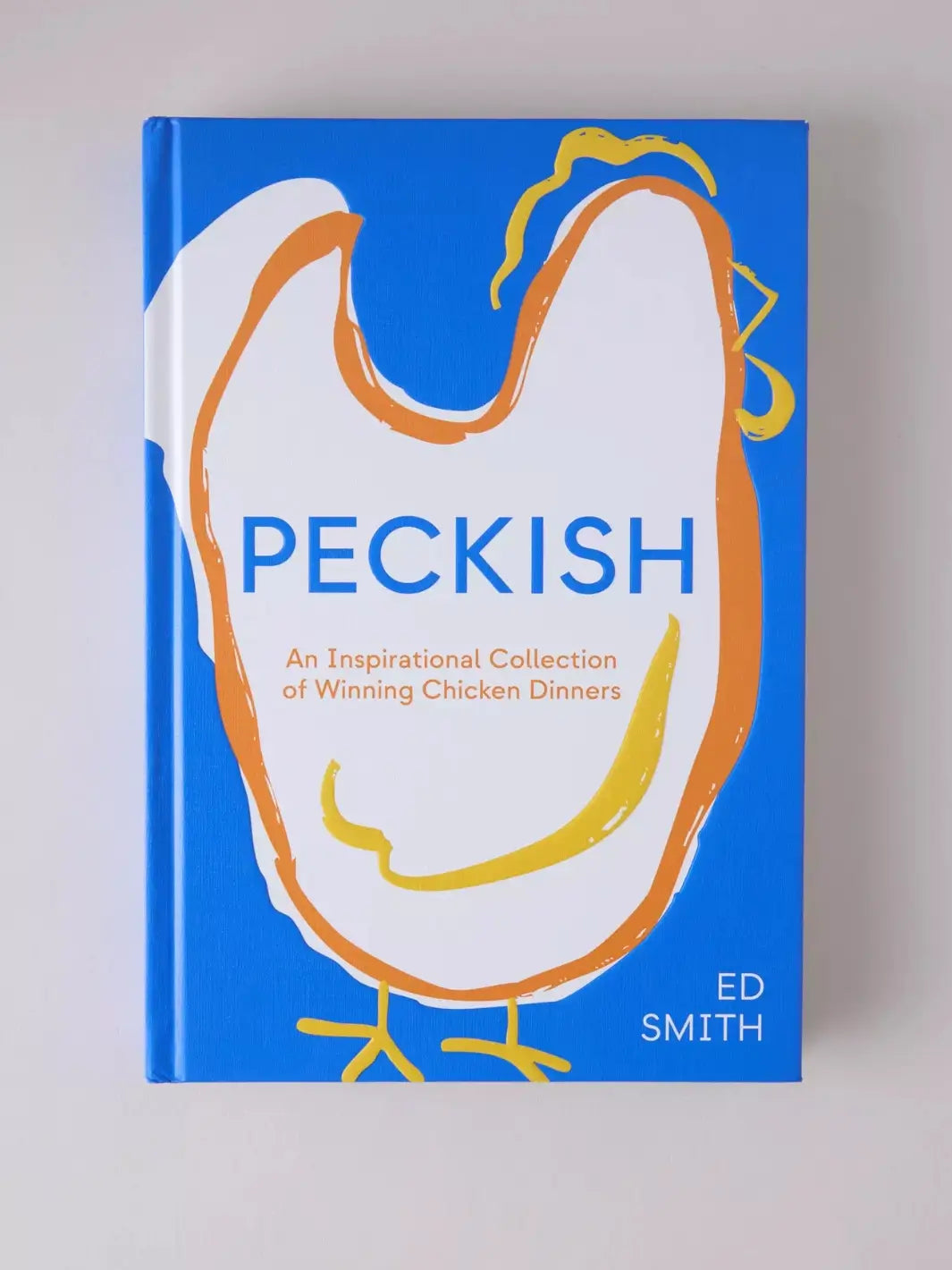 Hardback cover of Peckish: An Inspirational Collection of Winning Chicken Dinners by Ed Smith features a vibrant blue background centered with a minimalist, hand-drawn illustration of a chicken in white, orange, and yellow strokes | Twentyseven Toronto