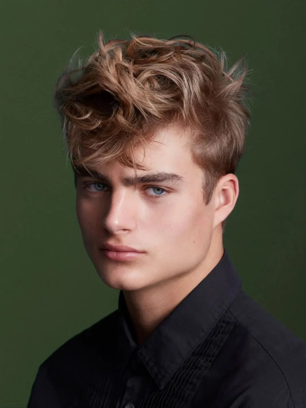 Blonde man with styled hair using the 'Perfect Mess' Soft Matt Styling Clay by Sam McKnight against a green background, 50ml | Twentyseven Toronto
