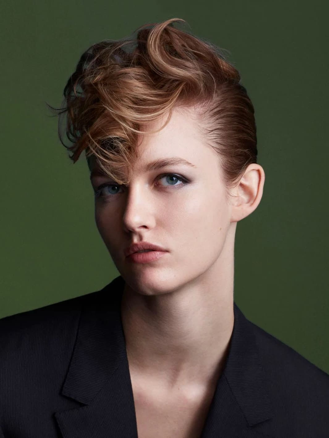 Woman with styled hair using 'Perfect Mess' Soft Matt Styling Clay by Sam McKnight against a green background, 50ml | Twentyseven Toronto