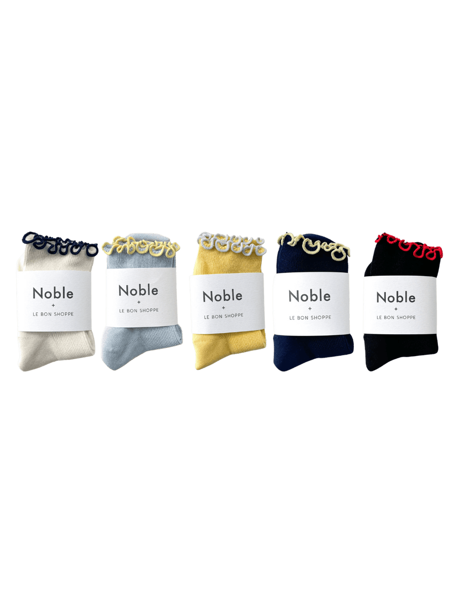 Five pairs of socks from the Le Bon Shoppe The Petite Ruffled Modal Socks Set - Pack of 5, each folded neatly with white "Noble + Le Bon Shoppe" paper bands | Twentyseven Toronto