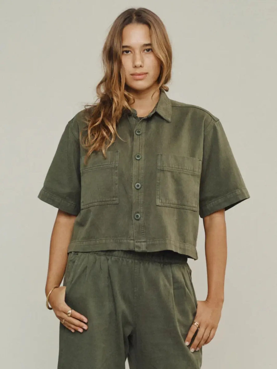A model from the waist up showcases the button-down front and double chest pockets of the cropped Jungmaven Phinney Twill Shirt - Olive Green | Twentyseven Toronto