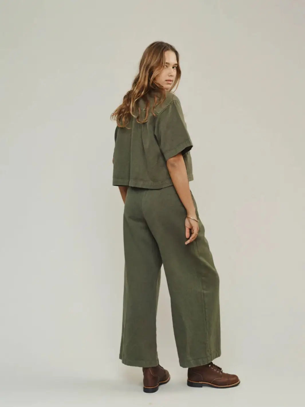 A three-quarter back view highlights the relaxed short sleeves and boxy silhouette of the Jungmaven Phinney Twill Shirt - Olive Green | Twentyseven Toronto