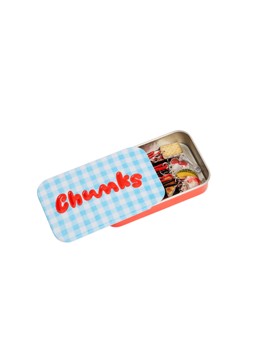 A red metal storage tin with a blue and white checkered lid featuring the red Chunks logo is shown partially slid open to reveal the Chunks Hairclips Picnic Bobby Pins inside | Twentyseven Toronto