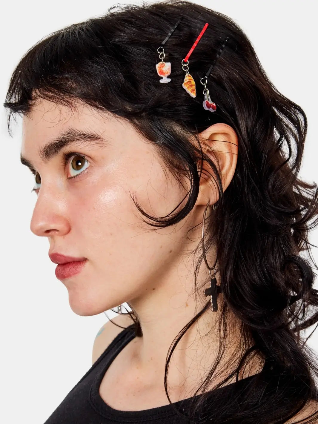 A person with dark wavy hair wearing three Chunks Hairclips Picnic Bobby Pins featuring food and drink charms dangling | Twentyseven Toronto