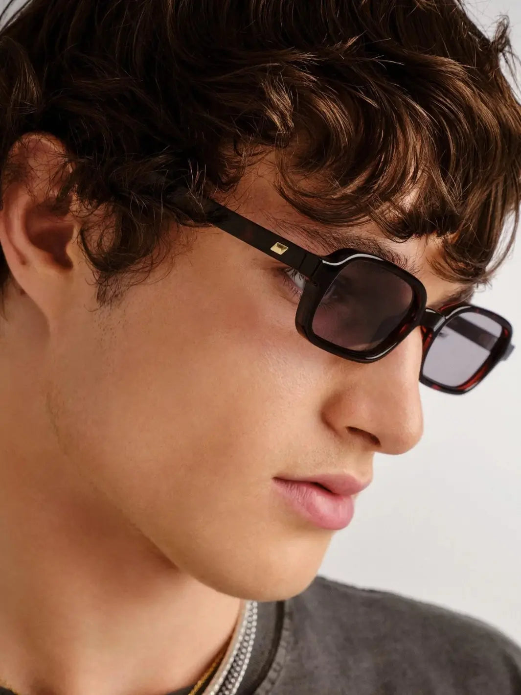 A close-up side profile portrait of a man looking downward while wearing the rectangular Le Specs Pilferer - Cherry Tort glasses | Twentyseven Toronto