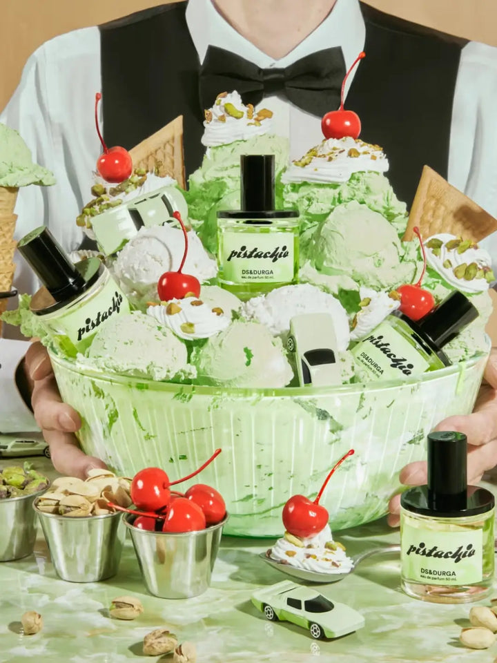 Green-themed gift basket with bottles of DS&Durga 'Pistachio' Eau de Parfum and decorative elements, held by a person | Twentyseven Toronto