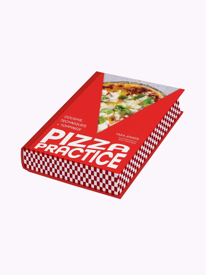 Front cover of the cookbook Pizza Practice: Doughs, Techniques + Toppings by Tara Jensen. Features a bold red cover with a "V" shaped cutout revealing a slice of pizza topped with burrata and fresh basil with edges that look like a classic red-and-white checkered pizza box pattern | Twentyseven Toronto