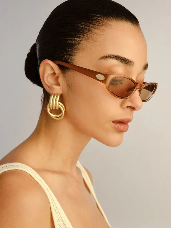 A side-profile view of a woman wearing an oval framed Le Specs Popalicious + | Pearl Caramel sunglasses | Twentyseven Toronto