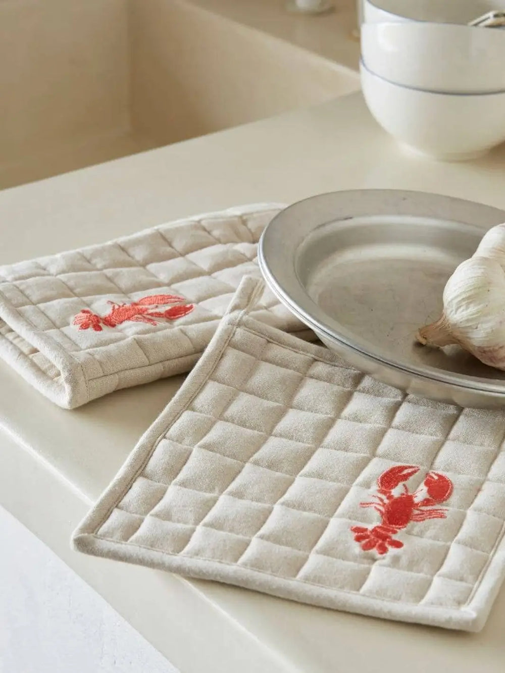 Quilted pot holders with red lobster design from Sylvie Thiriez on a kitchen counter | Twentyseven Toronto