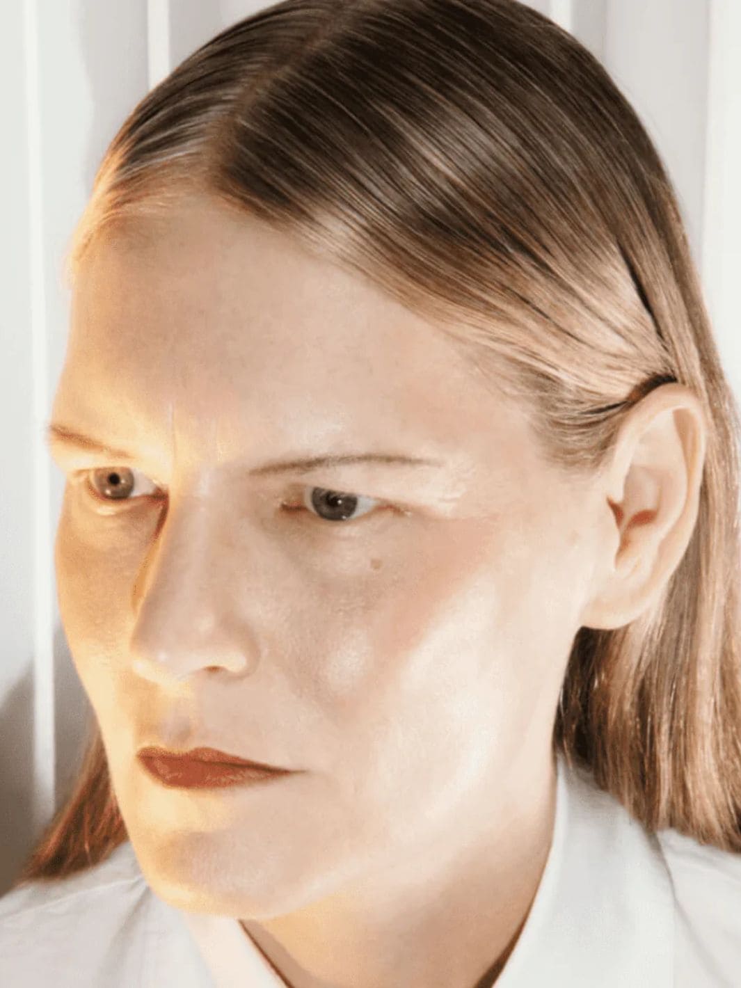 Close-up of a person with light brown hair and a neutral expression using 19/99 Beauty Precision Highlight Pencil in 'Oro' against a white background | Twentyseven Toronto