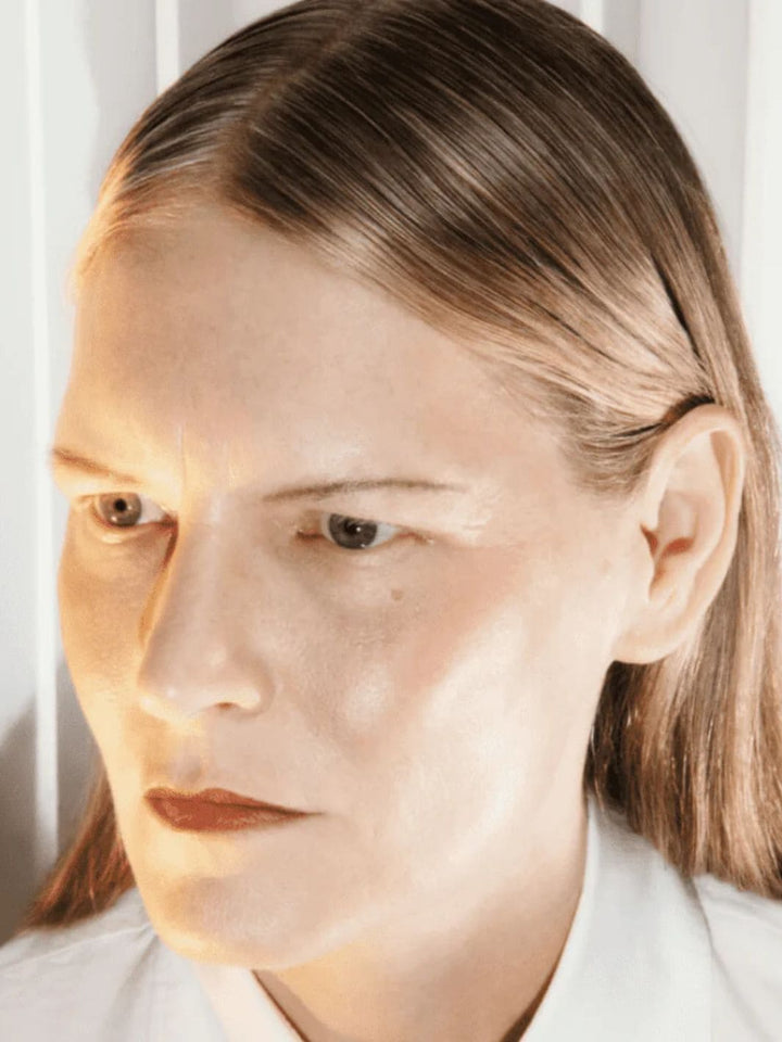 Close-up of a person with light brown hair and a neutral expression using 19/99 Beauty Precision Highlight Pencil in 'Oro' against a white background | Twentyseven Toronto