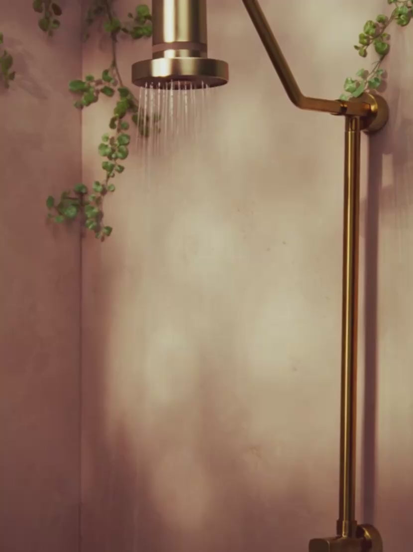 Video showing Jolie Skin Co The Filtered Shower Head in Brushed Gold being used in a shower room with branches of greenery | Twentyseven Toronto