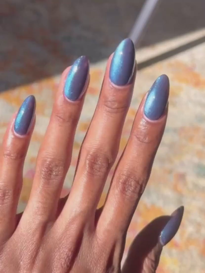 Hand demonstrates the dynamic cat-eye effect of Death Valley Nails Quietude (Or Swallowing Certain Unhappiness) Magnetic Nail Polish shifting the sparkling blue particles across a deep purple base | Twentyseven Toronto