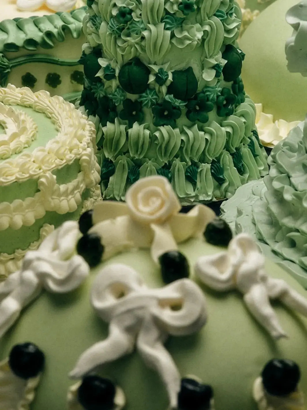 Extreme close-up shot highlighting intricate pale green and white frosting details on decorative cakes featuring the Flamingo Estate Prinsesstarta Milk Bar theme | Twentyseven