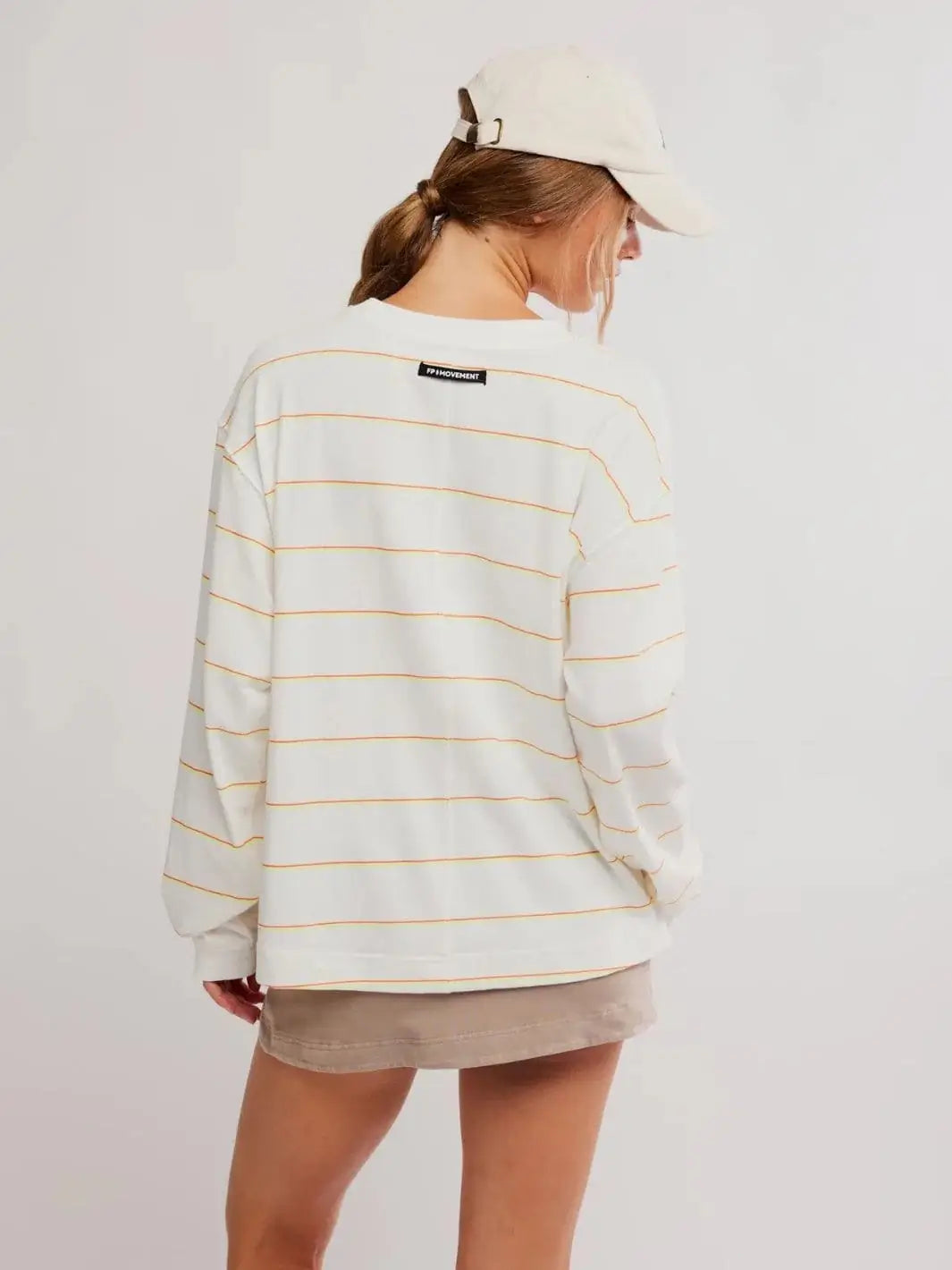 A rear view displays the prominent center back seam and small black FP Movement logo patch on the Free People Printed Hustle Layer in Awning Stripe Ivory | Twentyseven Toronto