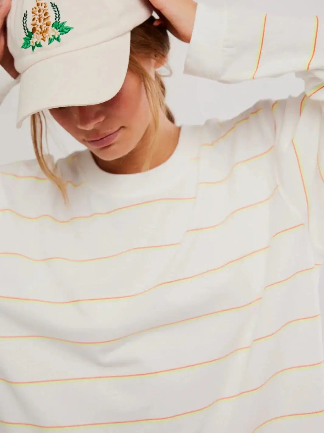 A close-up shot focuses on the thin neon orange and yellow horizontal stripes across the front of the Free People Printed Hustle Layer in Awning Stripe Ivory | Twentyseven Toronto