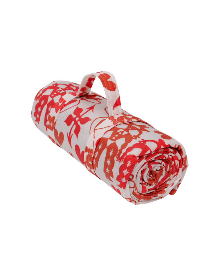 The Baggu Puffy Picnic Blanket in Cowgirl print rolled up in its built-in carrying handle, featuring a vibrant pink western "Cowgirl" motif on a transparent background | Twentyseven Toronto