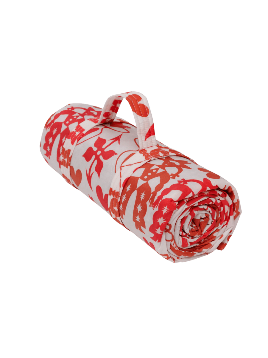 The Baggu Puffy Picnic Blanket in Cowgirl print rolled up in its built-in carrying handle, featuring a vibrant pink western "Cowgirl" motif on a transparent background | Twentyseven Toronto