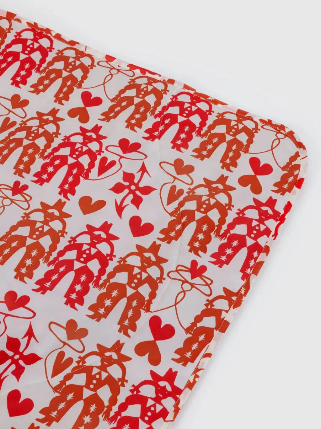 A close-up image of the Baggu Puffy Picnic Blanket - Cowgirl highlighting the quilted nylon texture and a whimsical print of pink boots, hats, and horseshoes | Twentyseven Toronto