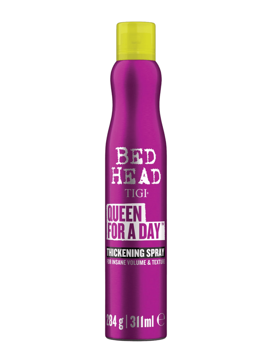 A hand wearing a gold link bracelet holds up a metallic purple bottle of Bedhead by TIGI Queen for a Day Thickening Spray | Twentyseven Toronto