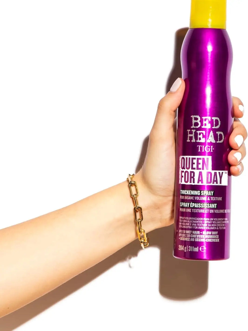 A metallic purple bottle of Bedhead by TIGI Queen for a Day Thickening Spray with a bright yellow cap against a plain white background | Twentyseven Toronto