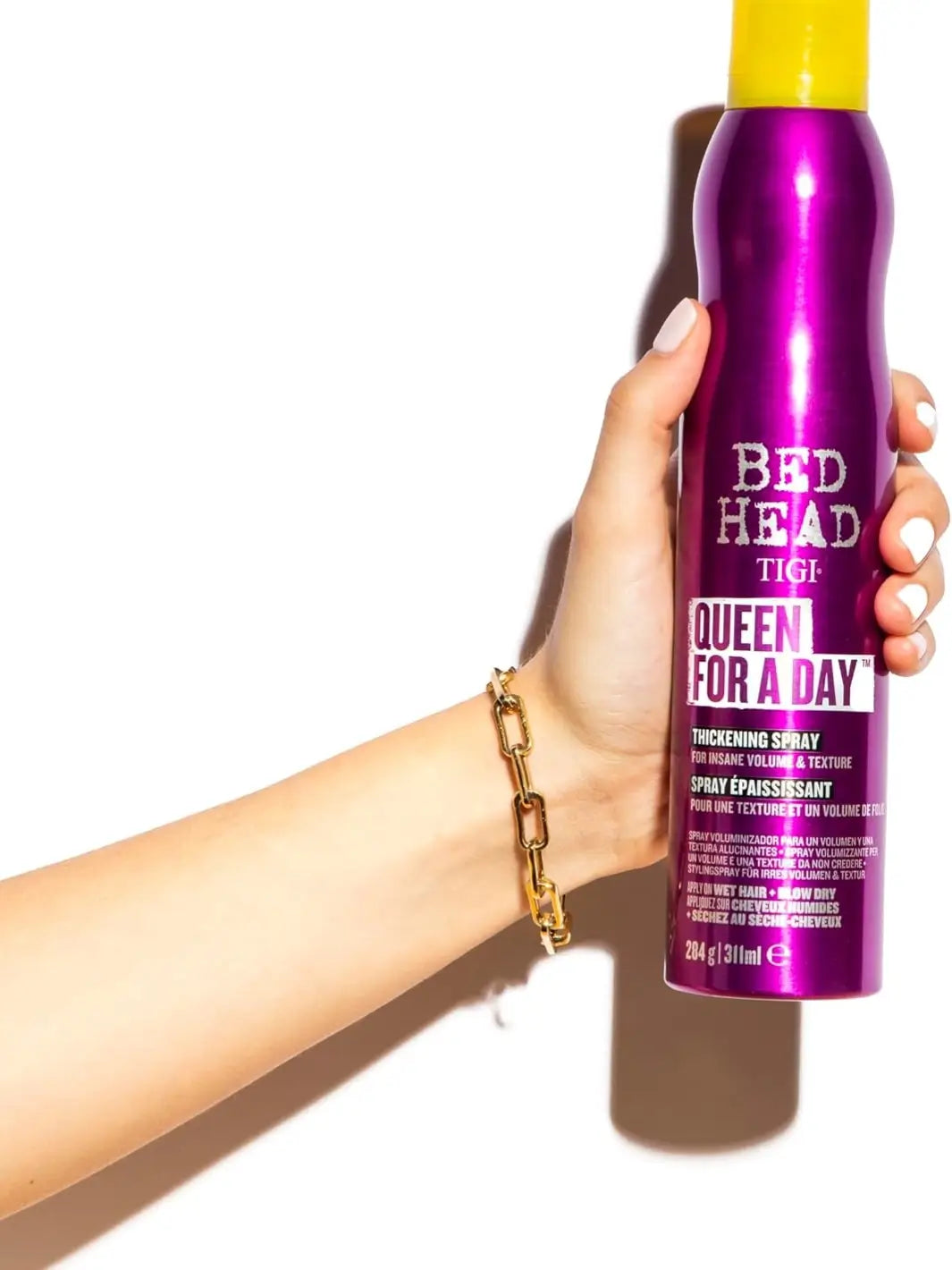 A metallic purple bottle of Bedhead by TIGI Queen for a Day Thickening Spray with a bright yellow cap against a plain white background | Twentyseven Toronto