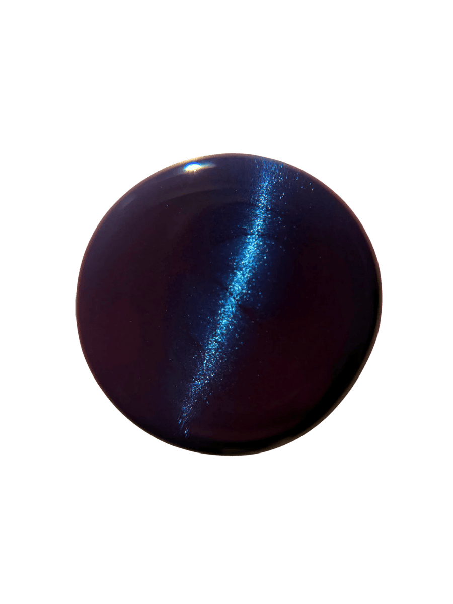 Circular color swatch on a white background displays a sharp, bright blue magnetic line running through the deep purple base of Death Valley Nails Quietude (Or Swallowing Certain Unhappiness) Magnetic Nail Polish | Twentyseven Toronto
