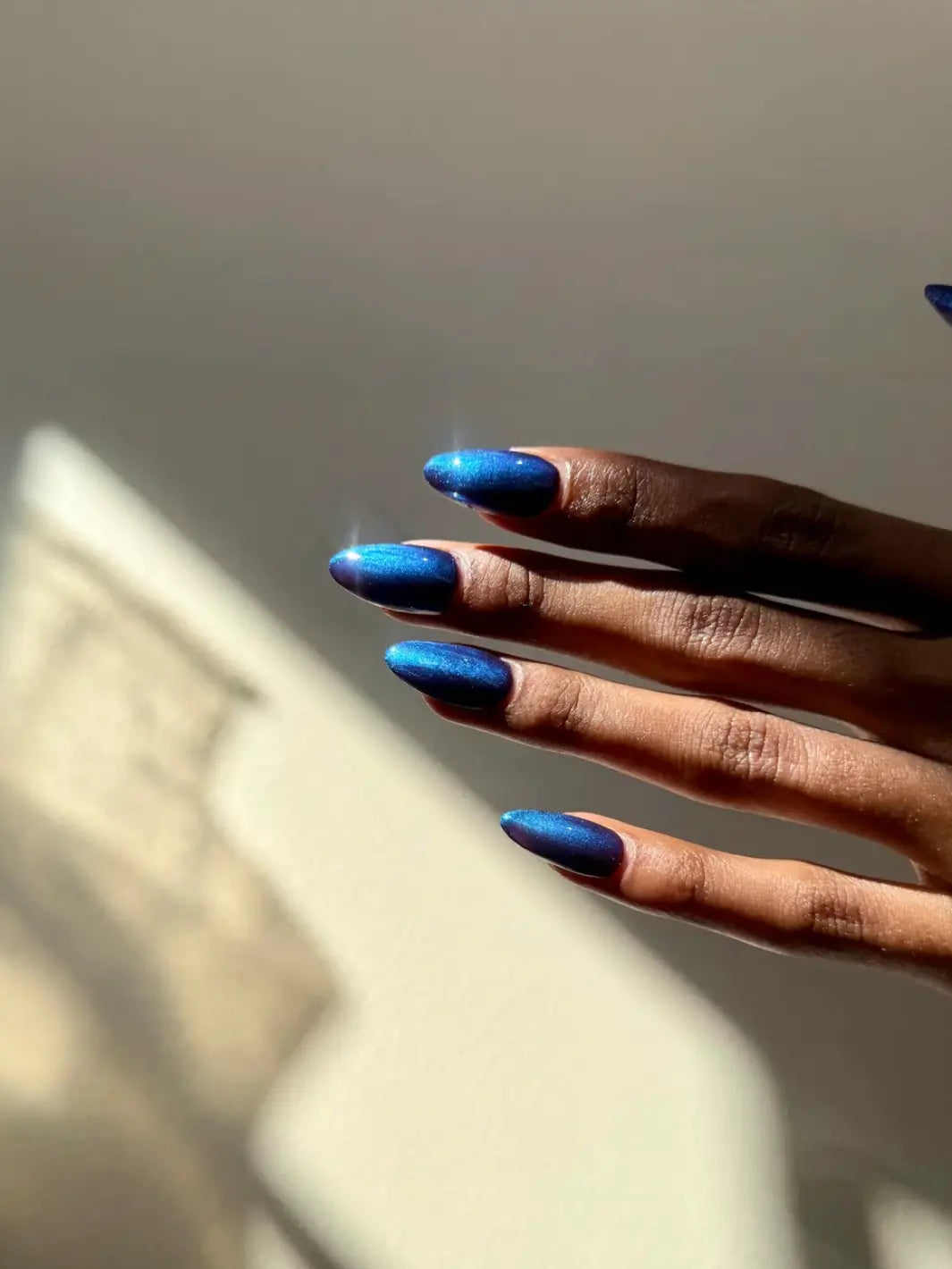 A hand with long, pointed nails is angled horizontally to display the velvet-like blue shimmer of Death Valley Nails Quietude (Or Swallowing Certain Unhappiness) Magnetic Nail Polish | Twentyseven Toronto