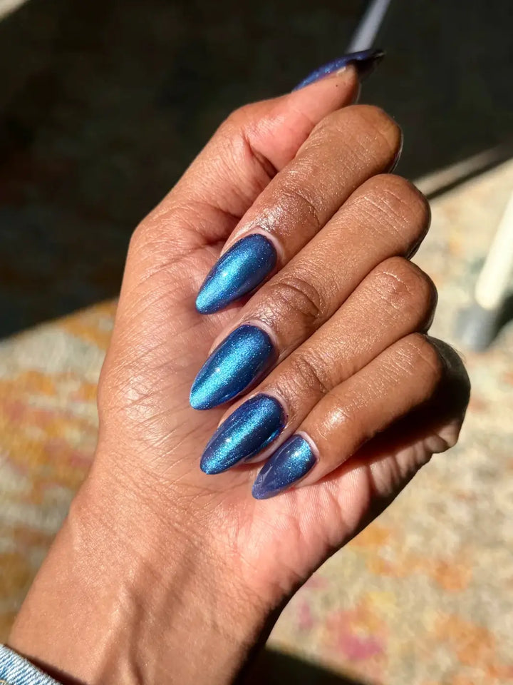 A hand with a deep skin tone and long nails showcases the multi-dimensional metallic blue shift of Death Valley Nails Quietude (Or Swallowing Certain Unhappiness) Magnetic Nail Polish | Twentyseven Toronto
