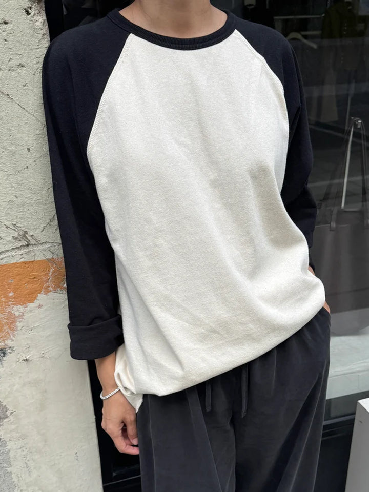 Model wearing Heavy Cotton Raglan Tee in Naturel/Black with a cream body, black raglan sleeves and relaxed fit, styled with charcoal drawstring pants | Twentyseven Toronto