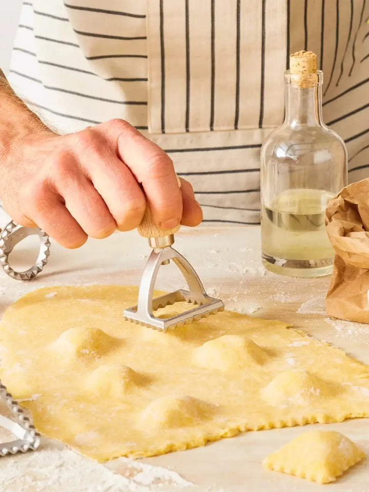 Person making ravioli with a pasta ravioli stamp from Burstenhaus Redecker on a kitchen counter | Twentyseven Toronto