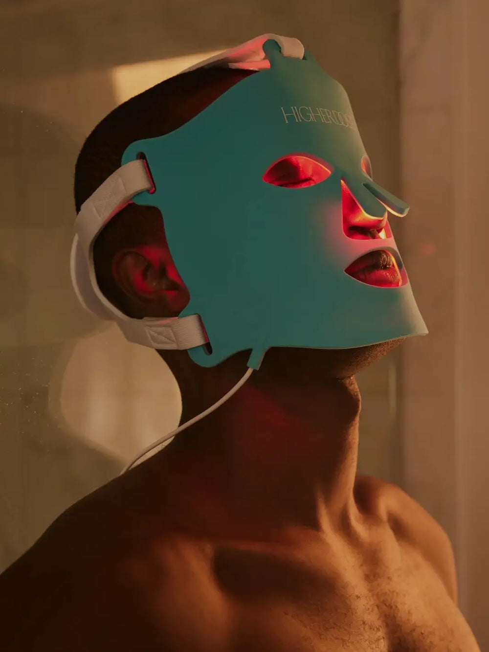Person wearing a blue red light face mask from Higher Dose in a dimly lit room | Twentyseven Toronto
