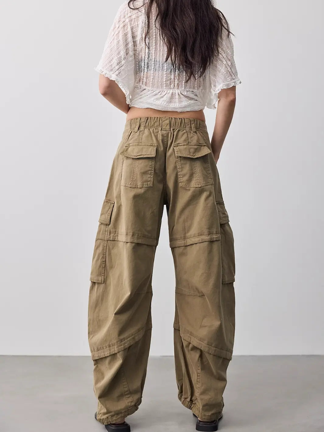 Back view of a model wearing Free People We the Free Reef Curved Twill Cargo Pants in Aloe displaying the rear flap pockets and elastic hem band | Twentyseven