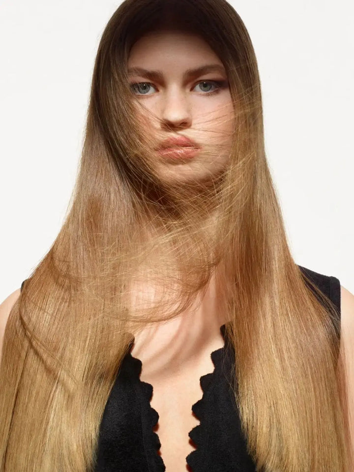 A blonde model with wind blowing across her face showcases her sleek, manageable locks treated with Hair by Sam McKnight Rich Nourishing Conditioner | Twentyseven Toronto