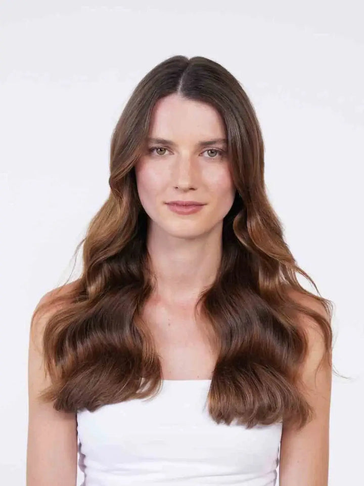 A woman with a white top faces forward to show off her long, healthy brunette waves after using Hair by Sam McKnight Rich Nourishing Conditioner | Twentyseven Toronto