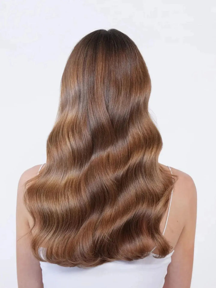 A back view reveals a woman's long, glossy brunette hair falling in smooth, perfectly defined waves after an application of Hair by Sam McKnight Rich Nourishing Conditioner | Twentyseven Toronto