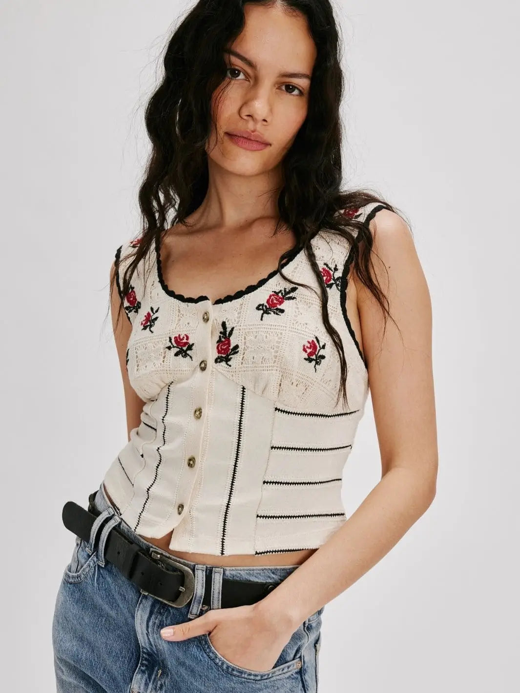 A model poses from the front wearing the fitted Free People Rose Bud Knit Top - Ivory Combo featuring front buttons, a scooped neckline, and embroidered rose details | Twentyseven Toronto