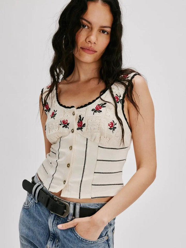 A model poses from the front wearing the fitted Free People Rose Bud Knit Top - Ivory Combo featuring front buttons, a scooped neckline, and embroidered rose details | Twentyseven Toronto